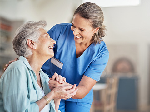 Eine ältere Frau im Pflegeheim wird von einer weiblichen Pflegekraft betreut.